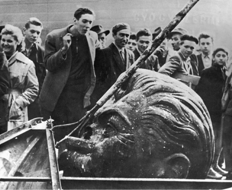 Studenti sbeffeggiano una statua di Stalin appena abbattuta.