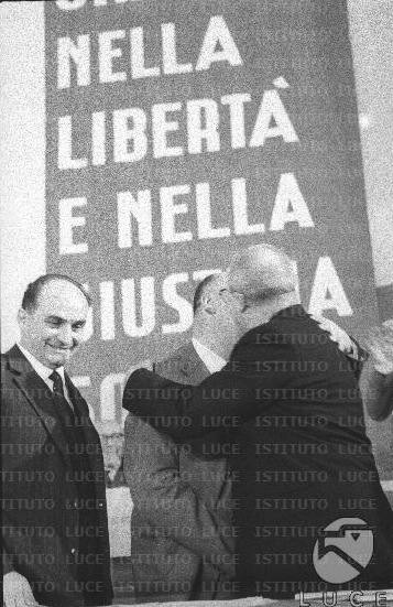 Saragat (a destra) abbraccia Reale sotto gli occhi di Tanassi sul palco del congresso PSDI.