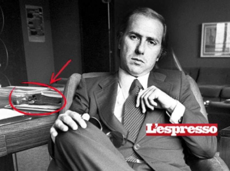 Foto dell'Espresso che mostra Berlusconi durante un'intervista, con una pistola sulla scrivania.